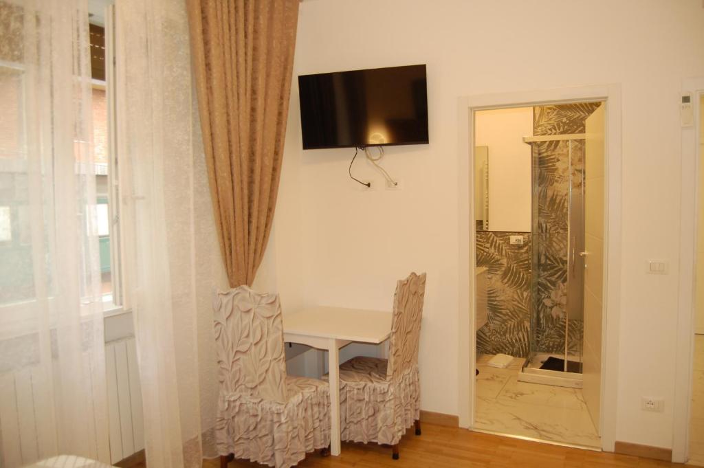a white table with two chairs and a television on a wall at Orchidea Stazione in Bologna
