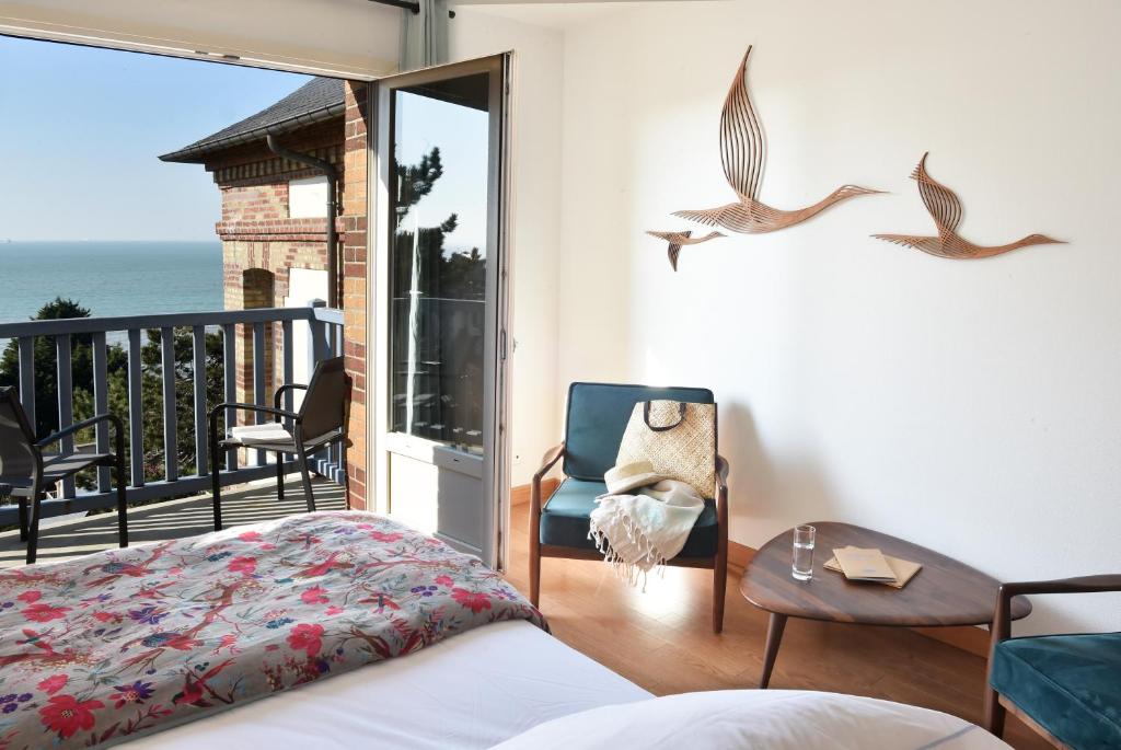a bedroom with a bed and a balcony with the ocean at Hotel Le Bellevue, Demeures & Chateaux in Villerville
