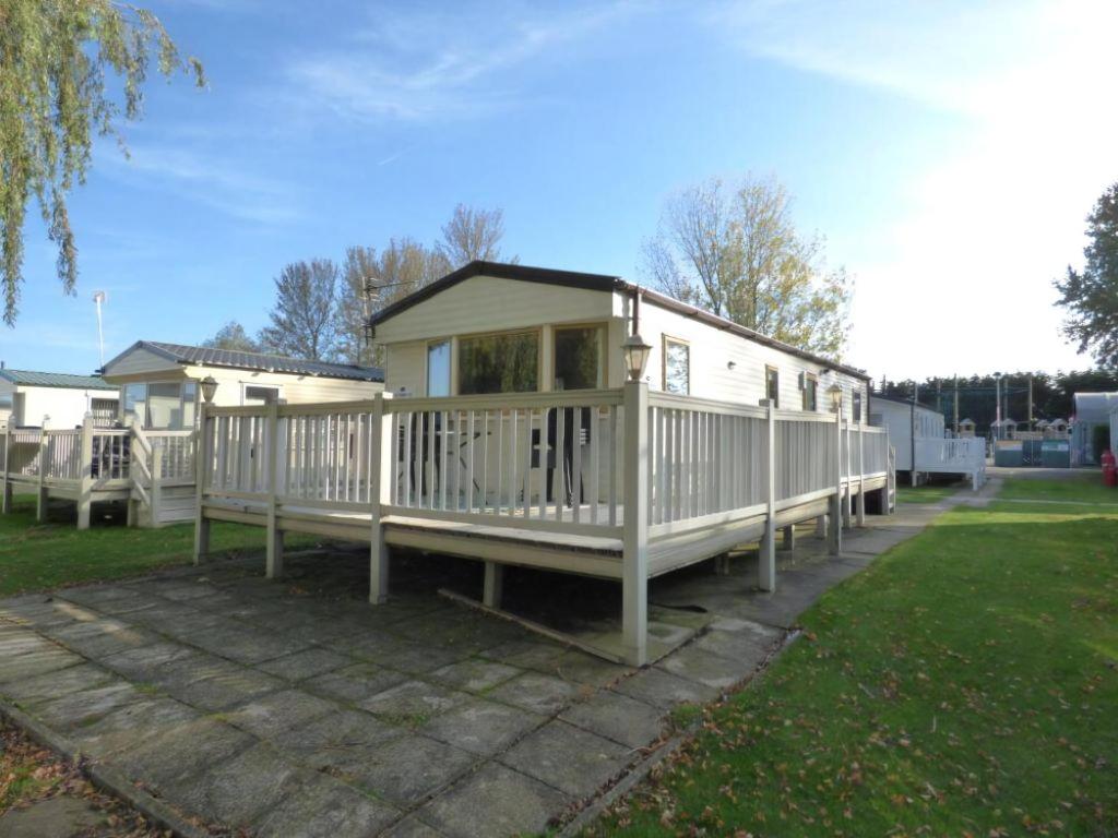 Una pequeña casa blanca con un porche en un patio. en Delightful Caravan With A Lake View At Southview Holiday Park Ref 33026Cl, en Winthorpe