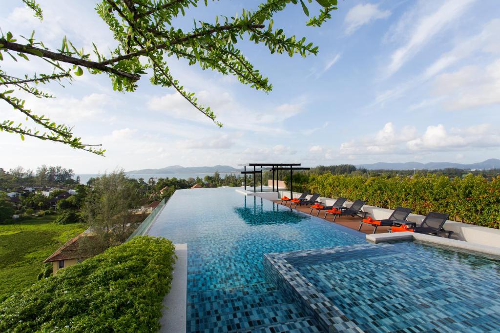 uma piscina de beiral infinito com cadeiras e vista para uma vinha em 6th Avenue Surin Beach em Praia de Surin