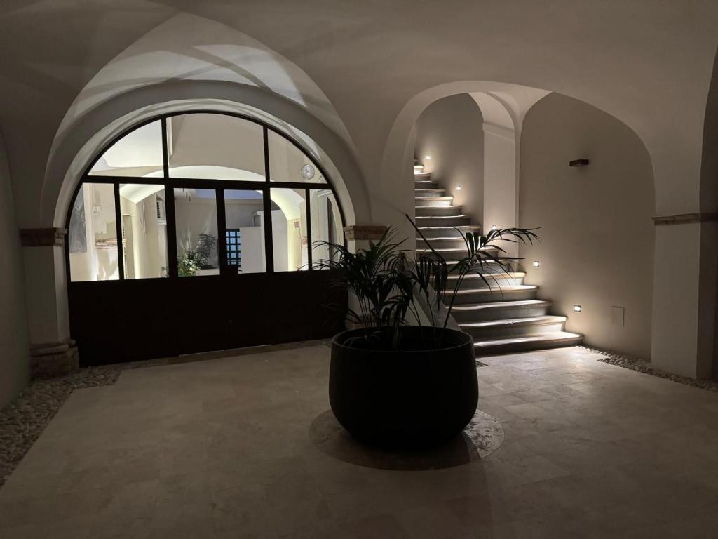 un hall d'entrée avec des escaliers et un grand pot avec une plante dans l'établissement La Corte Rental Room, à Teramo