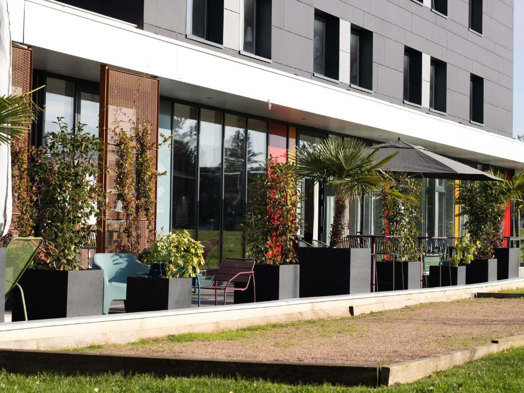 a building with potted plants on the side of it at ibis Gonesse Le Bourget in Gonesse