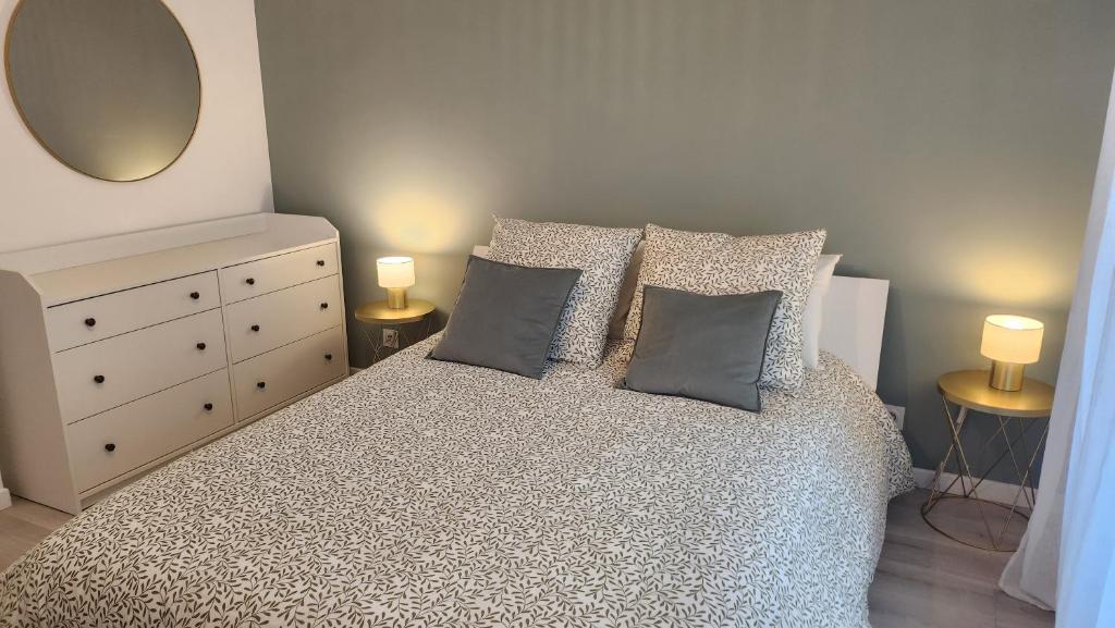 a bedroom with a bed with pillows and a mirror at Élégance et charme aux portes de Paris in Saint-Ouen