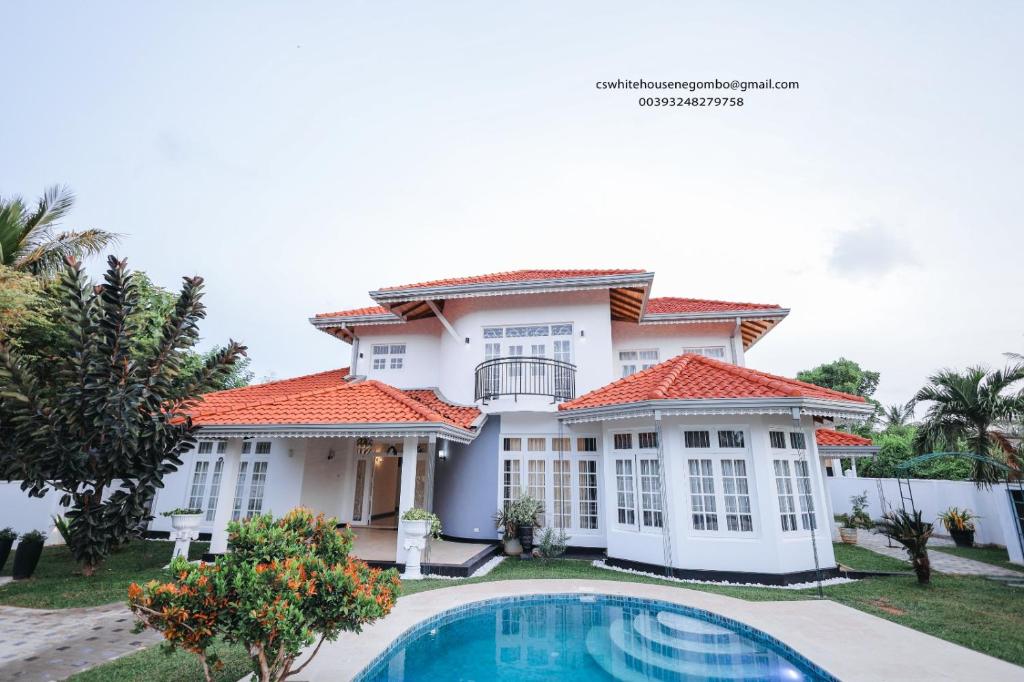 a house with a swimming pool in front of it at Cs white house negombo in Negombo