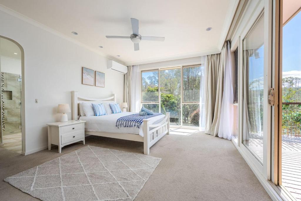 a white bedroom with a bed and a window at Peaceful Bushland Retreat with Treetop Hills Views in Wonga Park