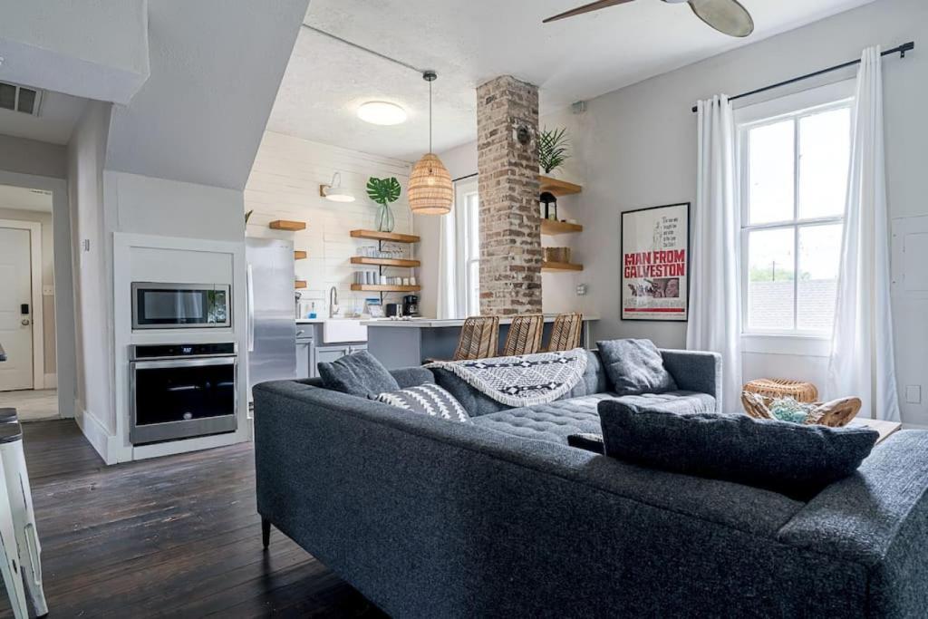 a living room with a couch and a kitchen at Historic and charming duplex in desirable midtown, close to the beach and strand in Galveston
