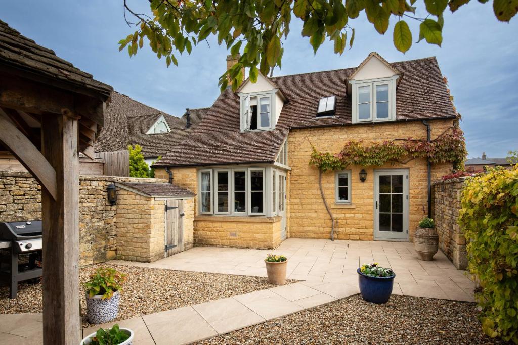 a brick house with a courtyard in front of it at Old Orchard Cottage in Moreton in Marsh