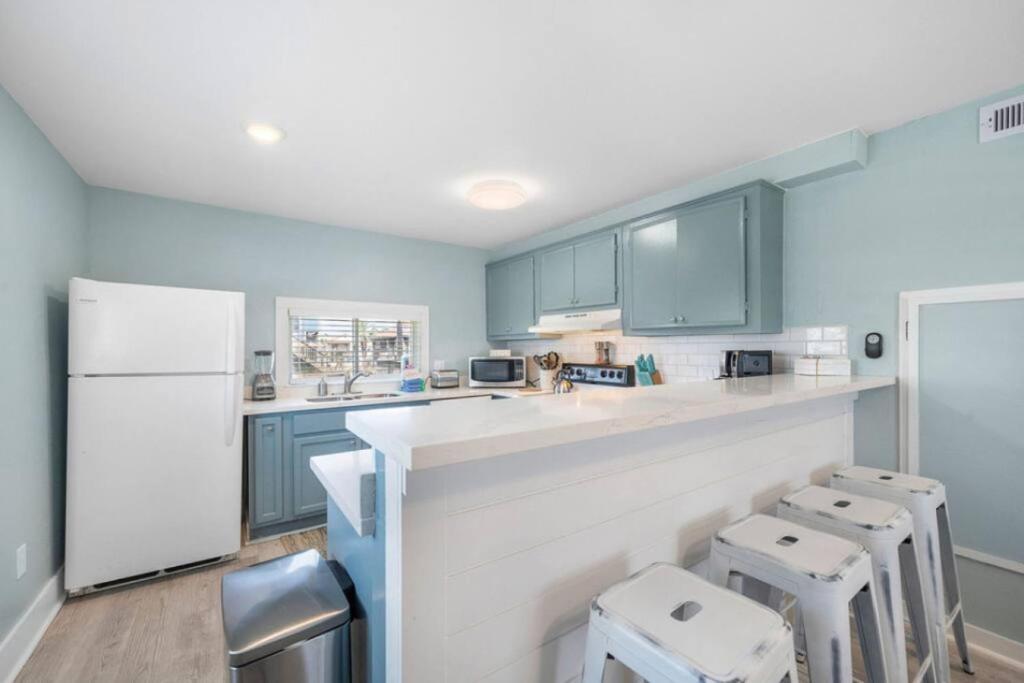 a kitchen with blue cabinets and a counter with stools at Cozy beach bungalow close to ocean with large yard in Galveston