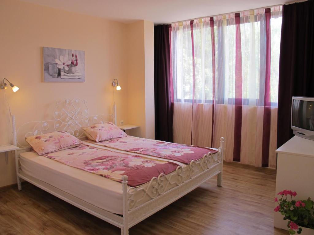 um quarto com uma cama com lençóis cor-de-rosa e uma janela em Guest House & Bistro Lefterova em Kotel