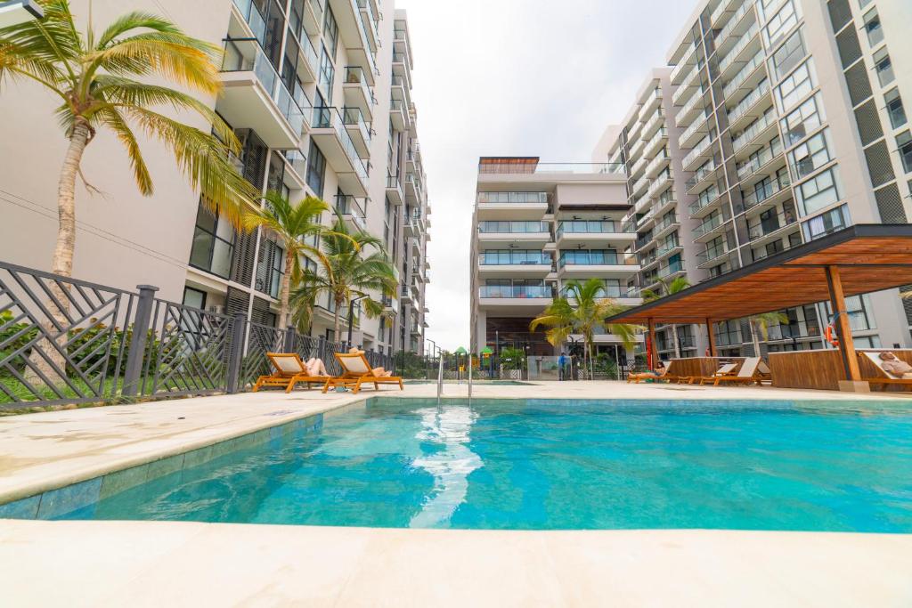 ein Swimmingpool mit Stühlen und Palmen und Gebäuden in der Unterkunft Nuevo apto familiar cerca al mar in Santa Marta