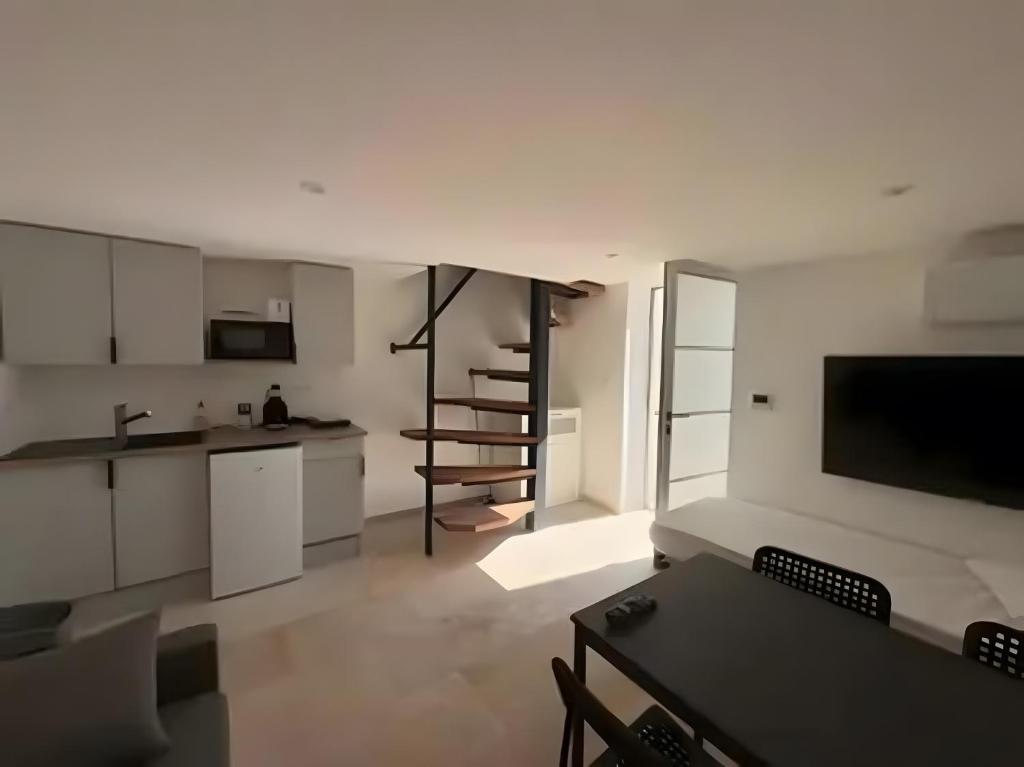 a kitchen and living room with white cabinets and a table at Canto Cigalo Duplex no 11 in Robion en Luberon