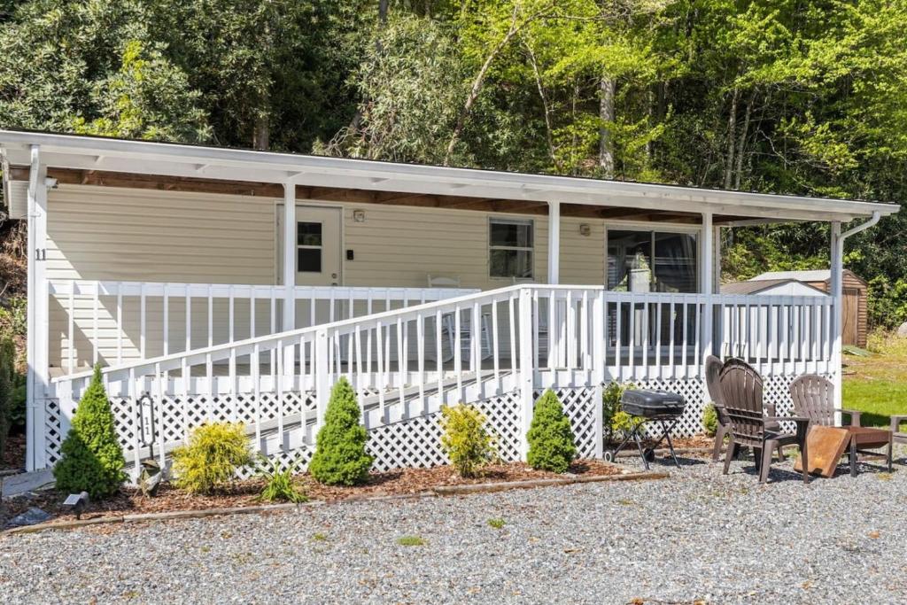 a white cottage with a white railing and a porch at Tucked Away - Magical Location on the River, Hiking, and Rafting in Dillsboro