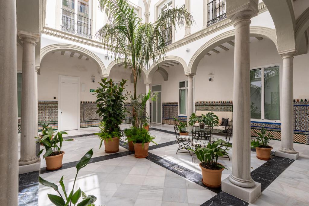 a lobby with palm trees and tables and chairs at Apartamentos Gravina 31 in Seville