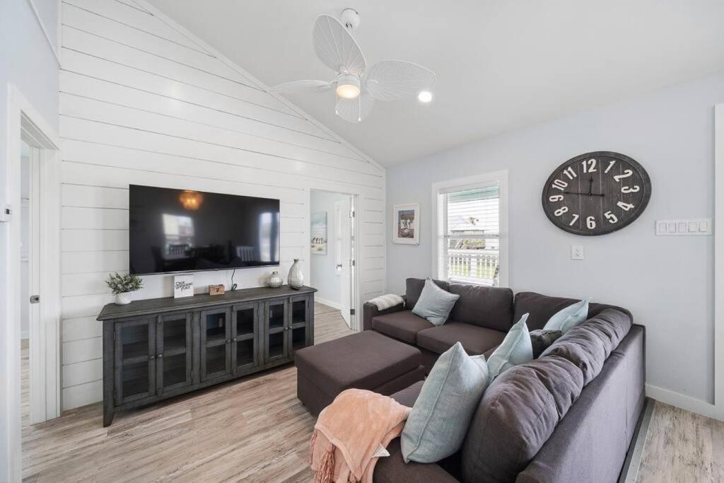ein Wohnzimmer mit einer Couch und einer Uhr an der Wand in der Unterkunft Beach bungalow with large, wrap-around deck, close to beach in Galveston