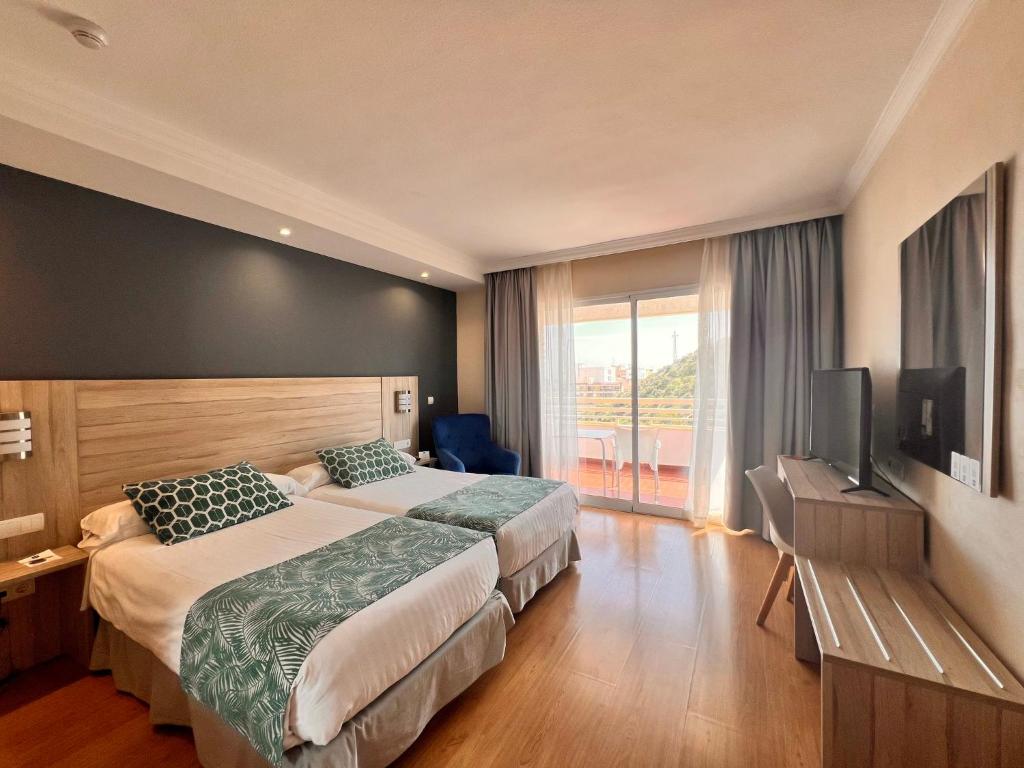 a hotel room with two beds and a flat screen tv at Sercotel Maya Alicante in Alicante