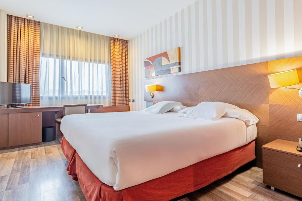 a hotel room with a large bed and a television at Sercotel Las Artes Pinto in Pinto
