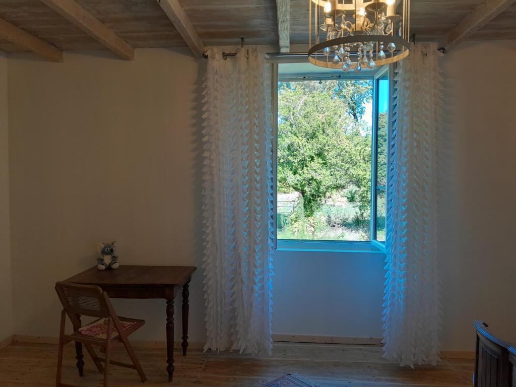 Saint-CybardeauxにあるChambre vue sur jardinの窓(テーブル、シャンデリア付)が備わる客室です。