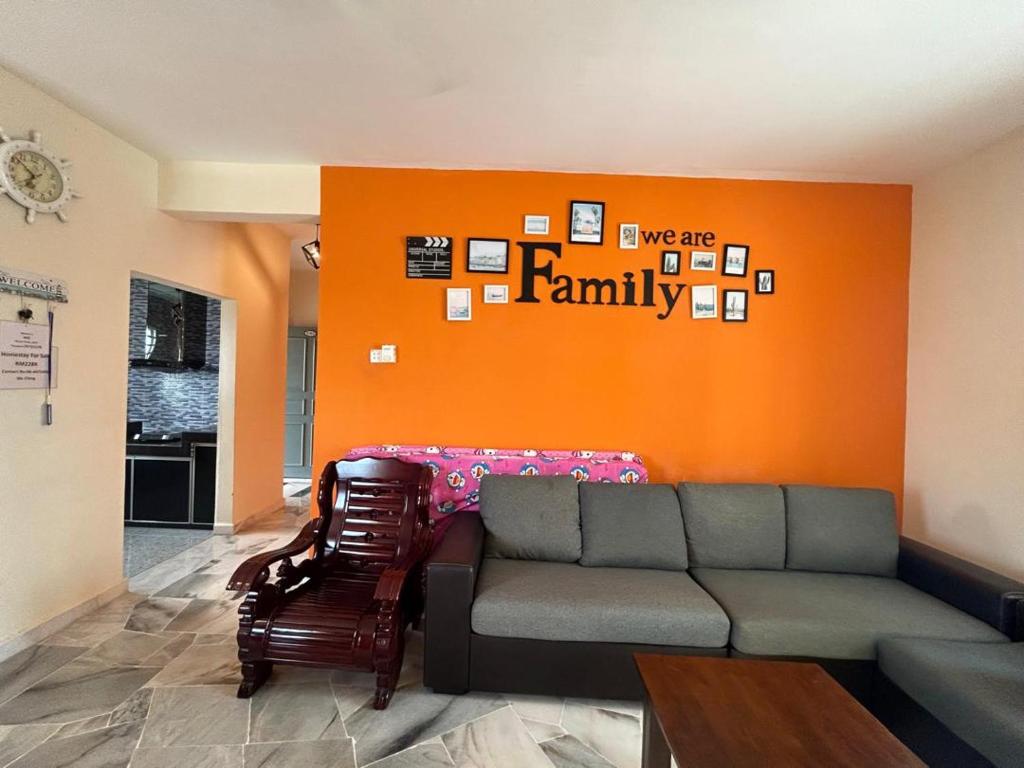 a living room with a couch and an orange wall at ALR Homestay Mvv in Port Dickson