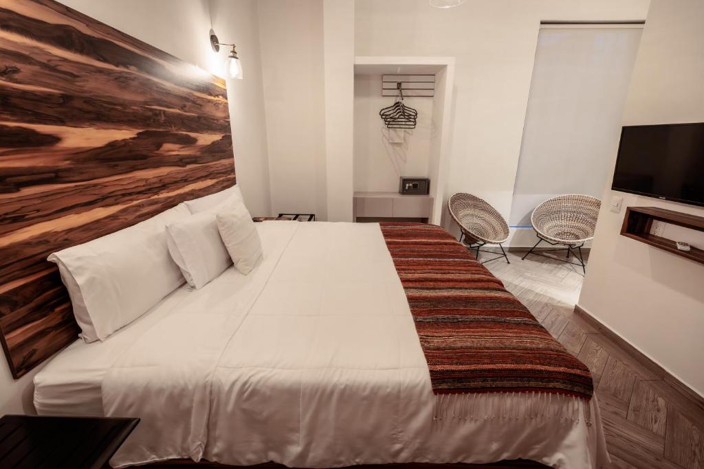 a bedroom with a large white bed with a tv at Hotel Tabáa Oaxaca in Oaxaca City