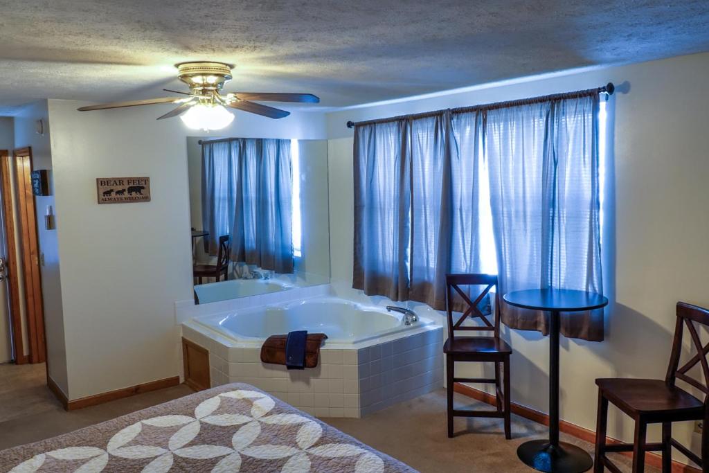 a bathroom with a tub and a bed and a ceiling fan at Bear Camp By The Night in Pigeon Forge