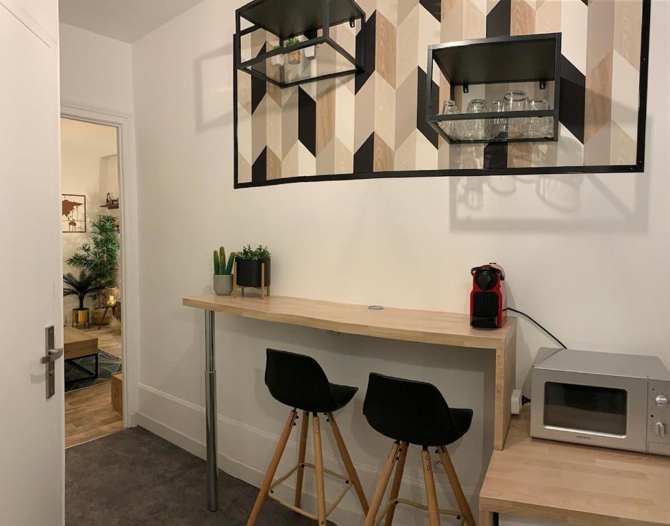 a room with a counter with stools and a microwave at Superbe studio proche centre ville in Beauvais