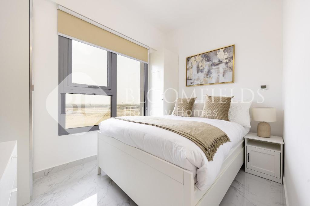 Una habitación blanca con una cama y una ventana en Bloomfileds Memorable 2br Duplex Masdar City, en Abu Dhabi Intl