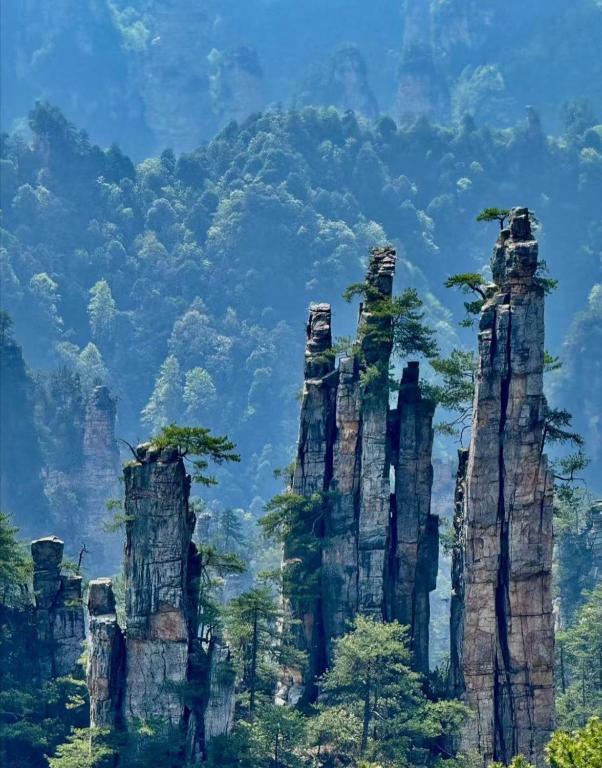 un grupo de rocas altas en las montañas en GUI YUAN ZHEN PIN HOTEL,Approximately 3km away from the east gate of Zhangjiajie National Forest Park,Free Chinese western Breakfast,Free Self-Service Laundry , Attraction Tickets Serivce in advance,Free one-way shuttle service for 4 nights or more, en Zhangjiajie