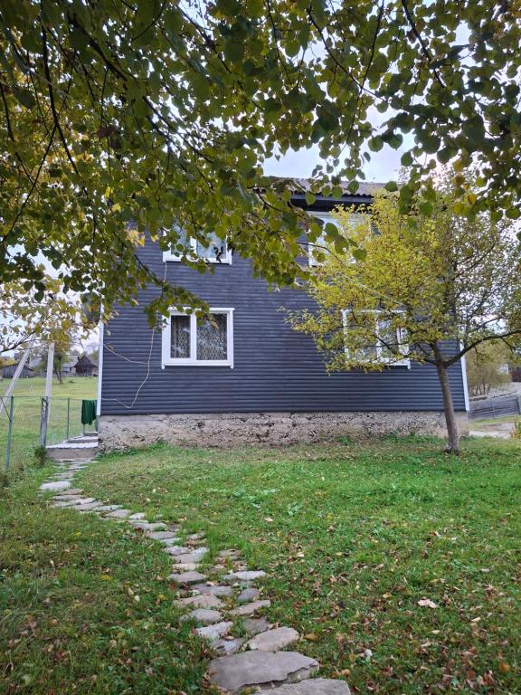 a blue house with a tree and a stone path at U Ilka in Lazeshchyna
