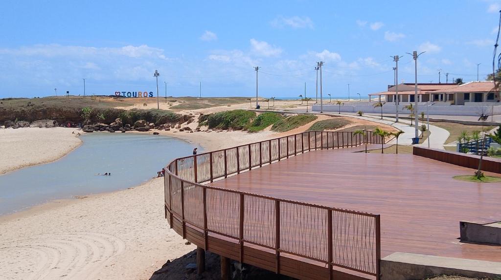 a wooden boardwalk on a beach next to a body of water at ORLANDO CITY PARK área de camping in Touros