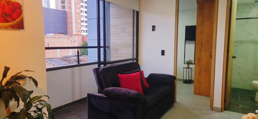 a living room with a black chair with a red pillow at Apartamento exclusivo en Sabaneta, Antioquia in Sabaneta