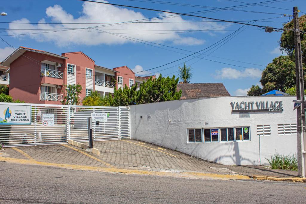 Un edificio con una valla blanca y una calle. en Ponta Negra_Apto Completo, en Natal