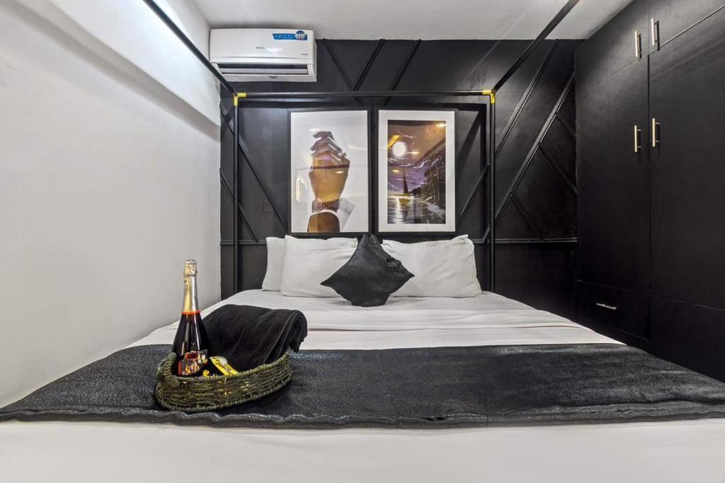 a small bedroom with a bed with a bottle of champagne at Noir & Blanc Suite in Mama