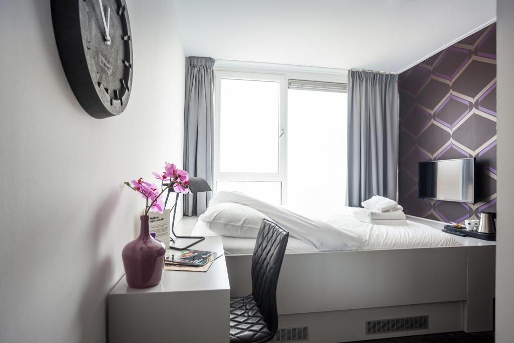een slaapkamer met een bed en een bureau met een vaas met bloemen bij Stravinsky Slapen in Hengelo