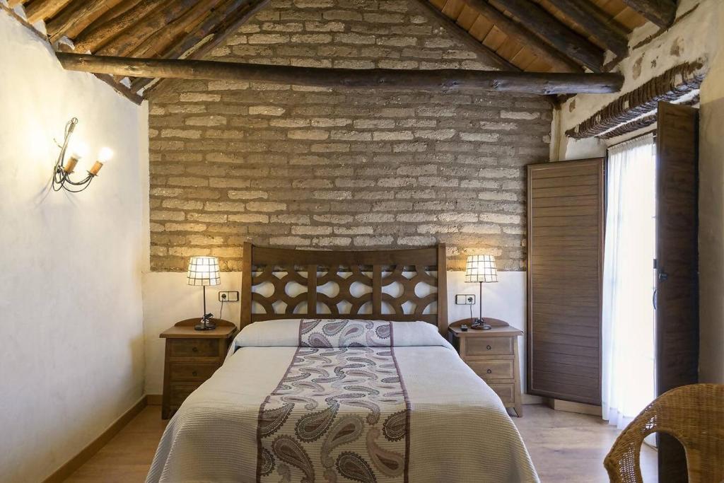 a bedroom with a large bed and a brick wall at Casa Rural Abuelo Pedro in Cuerva