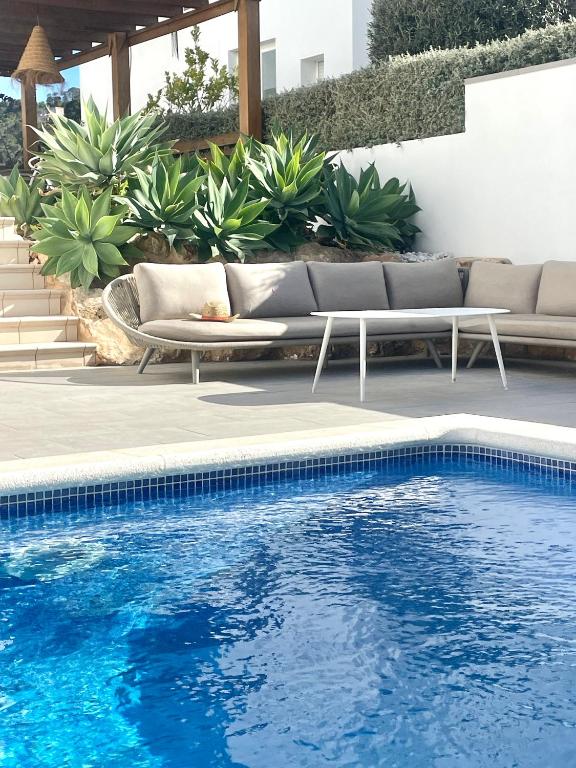 a swimming pool with a couch and some plants at Casa Bonic -Sunset Seaview in Sant Josep de Sa Talaia
