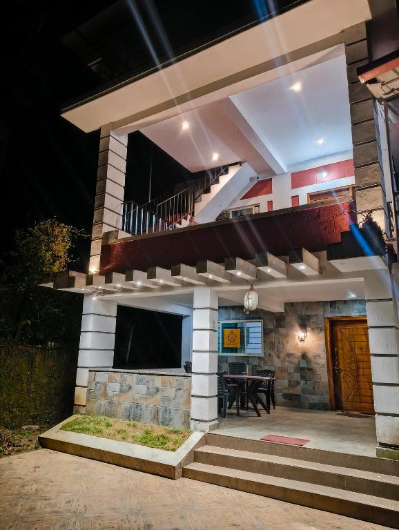 a house with a staircase leading to a patio at night at Amberleaf Estate 4BHK Homestay Coorg by Homeyhuts in Virajpet