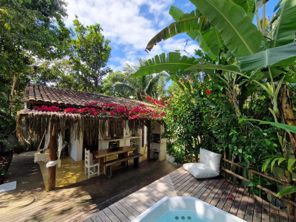 una casa con flores rojas en el techo en Mini Casa com Jacuzzi e Piscina, en Trancoso