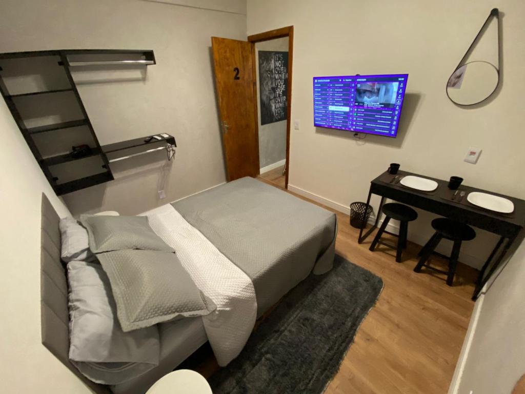 a bedroom with a bed and a desk and a television at Apartamento compartilhado em Guarapuava - Quarto 2 in Guarapuava