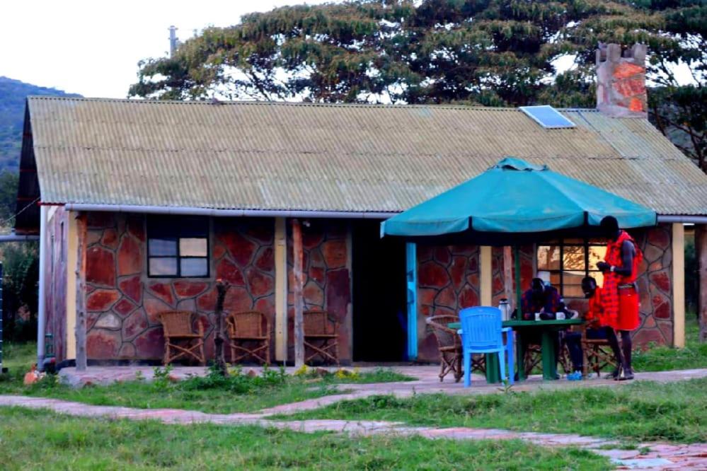 a woman standing in front of a house with a table at Semadep Village Guest House in Sekenani