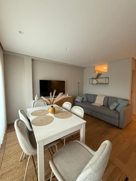 Una sala de estar con una mesa y sillas blancas. en Apartamento do Raio, en Braga