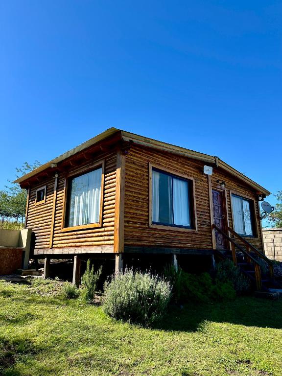 a wooden house with windows on a grass field at Villa Nicolasa in Villa Yacanto