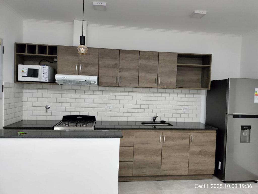 a kitchen with wooden cabinets and a sink and a refrigerator at La Estancia de lolita in Olavarría