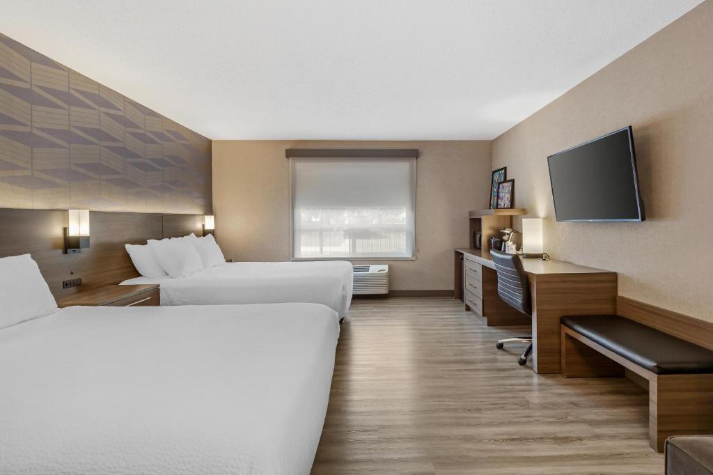 a hotel room with two beds and a flat screen tv at Best Western Plus West Edmonton in Edmonton