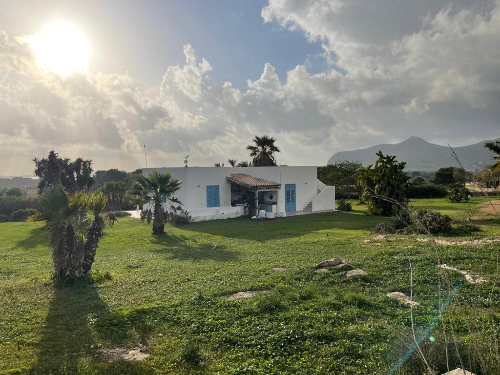 een wit huis in een veld met palmbomen bij La Villa di Nina in Favignana
