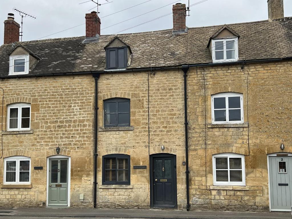 un antiguo edificio de ladrillo con ventanas y una puerta en Elm Cottage, en Moreton-in-Marsh