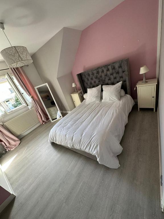 a bedroom with a large bed with a pink wall at Spacieuse et agréable à séjourner in Garges-lès-Gonesse