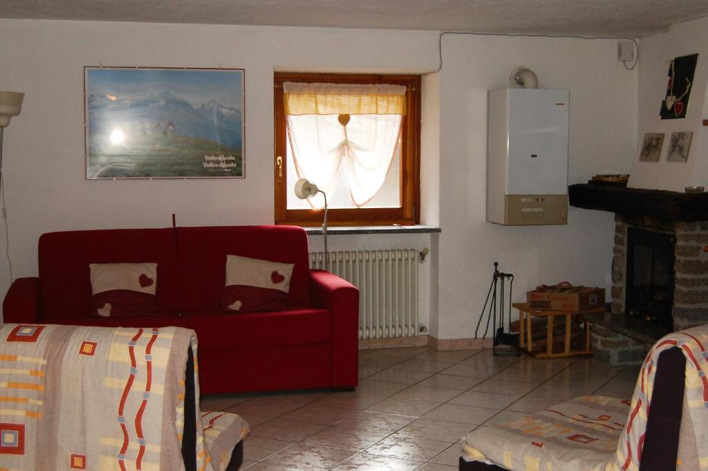 a living room with a red couch and a window at Case Gran Paradiso Rhemes Saint Georges Vieux in Rhemes-Saint-Georges