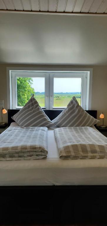 a bed with two pillows in front of a window at Haus Königsstieg in Struckum