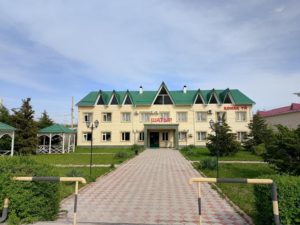 a large yellow building with a green roof at Гостиница Шатыр in Saryaghash