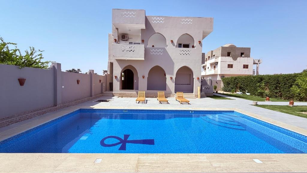 a villa with a swimming pool in front of a house at Magic Garden Guest House in Luxor